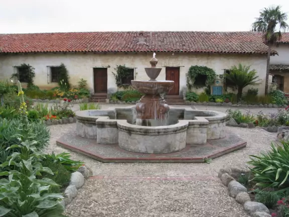 Rustic-looking fountain and buildings in front courtyard.