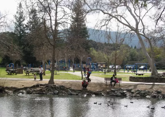 Parents and kids enjoying the creek beside the playground at Vasona Lake Park.