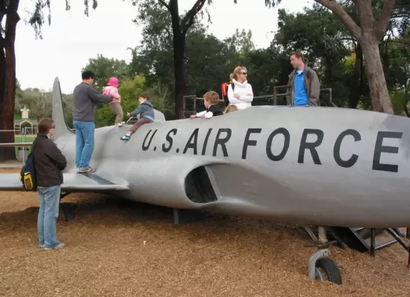Kids sit in the cockpit and climb on the wings of the fighter plane at Oak Meadow Park.