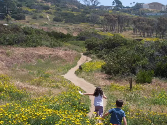 Kids run for joy toward the trail at Sunset Cliffs Natural Park.