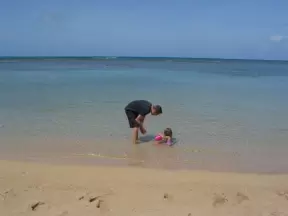 A father and baby girl in the calm waters close to shore. 