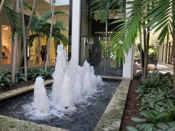 Ultra rich outdoor mall with gorgeous plants, fountains, sculptures, and flowers.