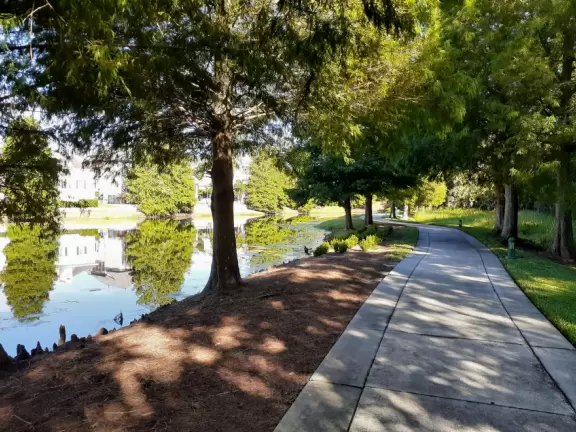 A popular town center with sidewalk cafes leading down to a pretty lake with a walking path.