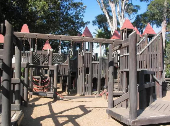 Giant wooden castle playground set among tropical palms.