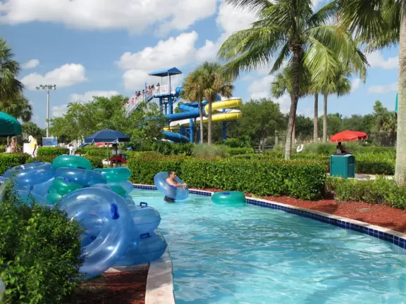 Colorful waterpark with splash playground, lazy river, lily pad walk (monkey bars over water) and two waterslides.