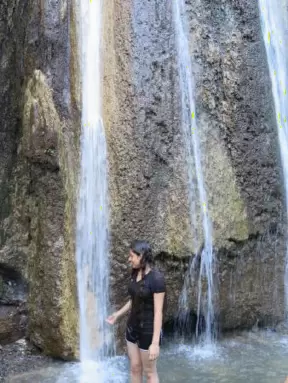A young woman gets her feet wet at the foot of the falls.