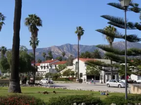 View of mountains, Norfolk pine, and palm trees at little park by the train station.

