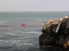 Kayakers paddle around the point.