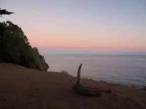 A lone log and sunset over the sea.
