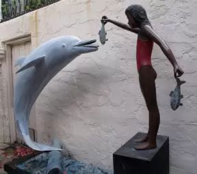 Statue of girl feeding a fish to a dolphin, in Gucci Courtyard.