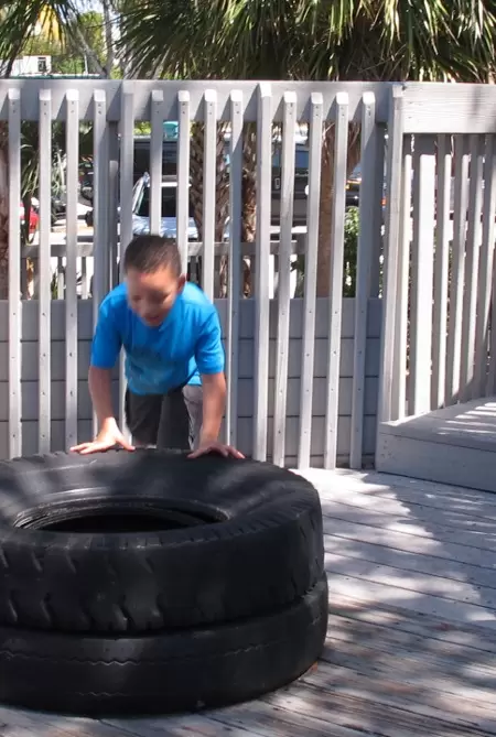 A boy explores stacked tires.