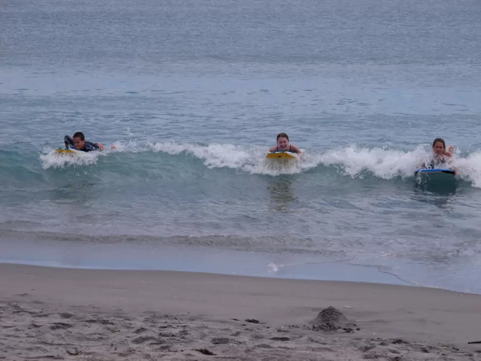 Kids bodyboard in to shore on an April day.