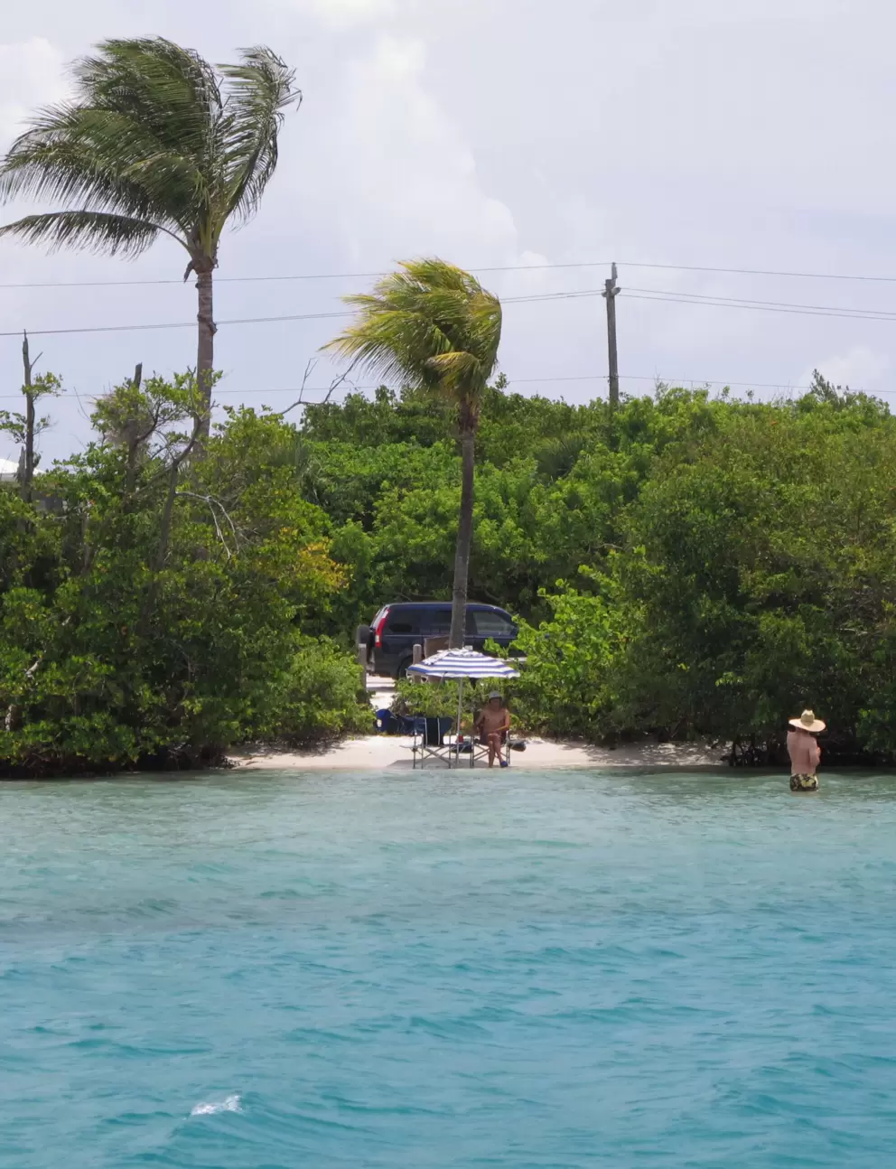 A guy with straw hat swims at a little beach at Coral Cove!