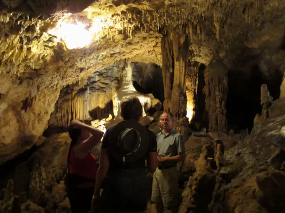 A tour guide talks with two travelers inside the cave.