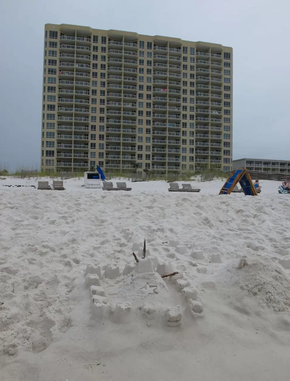 Sandcastle on the shore and highrise in the distance.