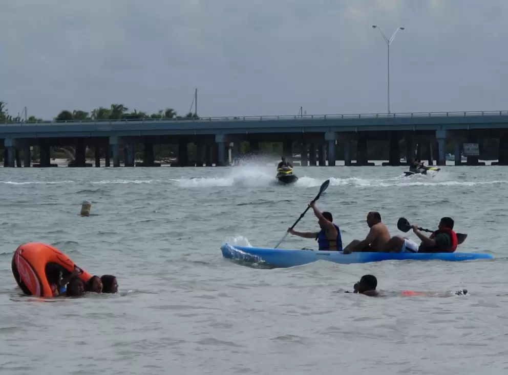 Jet skis, kayak, and raft tipping over, by the causeway.