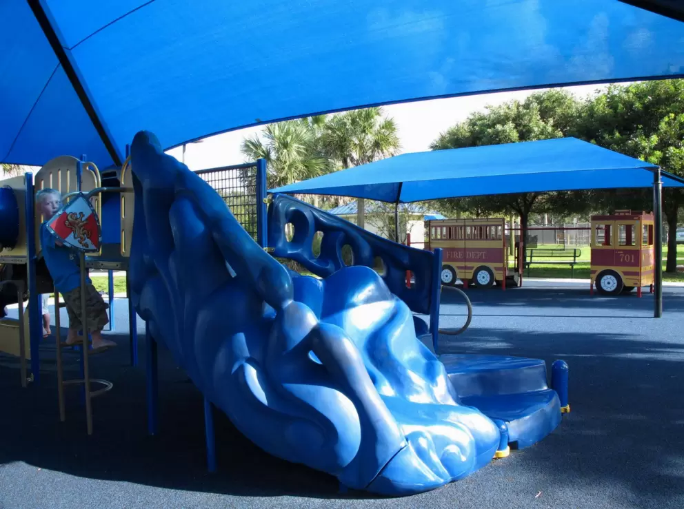 A boy pretends to be a knight under the blue canopy.