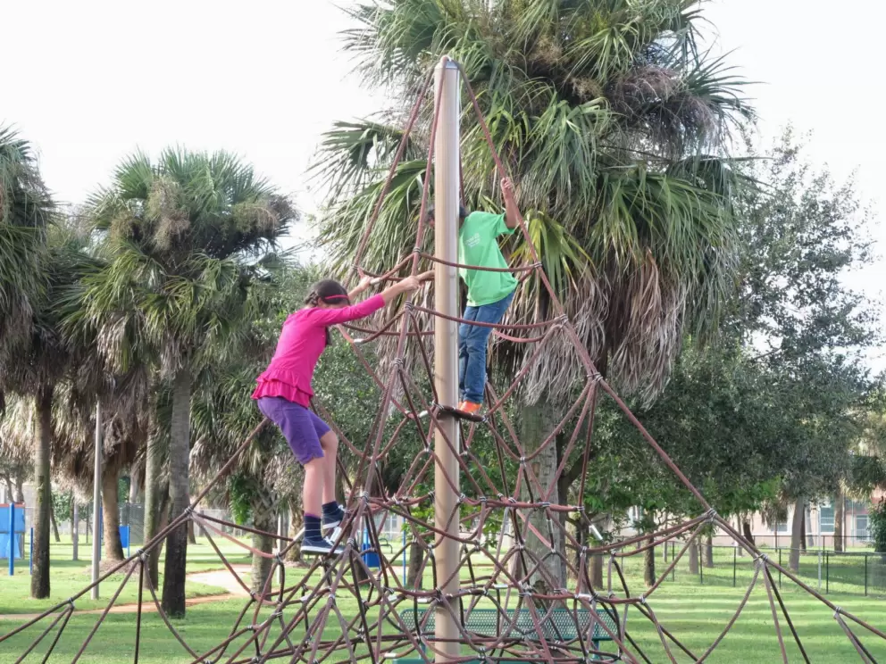 Two girls climb at the top of the space net.