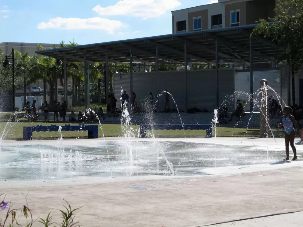 Water play at the splash pad. Behind, the amphitheater provides shade for parents.