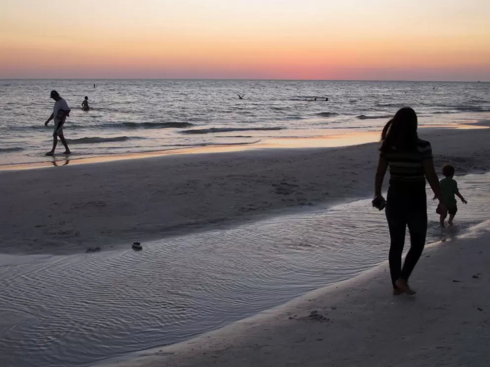 A mother follows her child as he explores the shore.