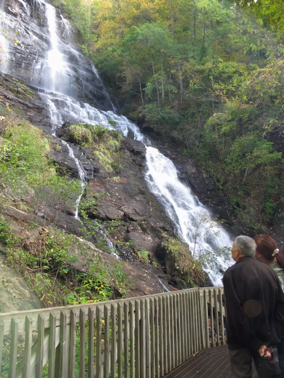 Two visitors look up at the falls.