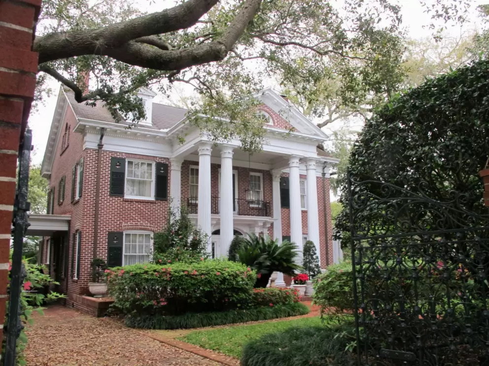 Historic brick mansion and large tree.