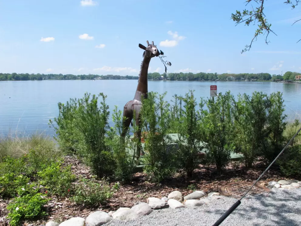 Giraffe sculpture beside the water.