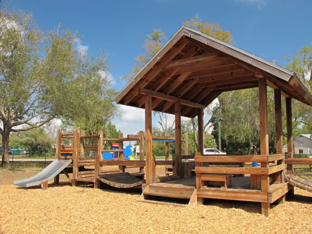 The shaded house, wooden bridge, and metal toddler slide.