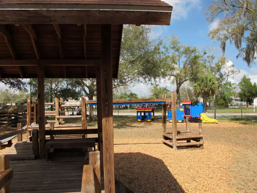 Blue and yellow pretend train, and shaded wooden playground.