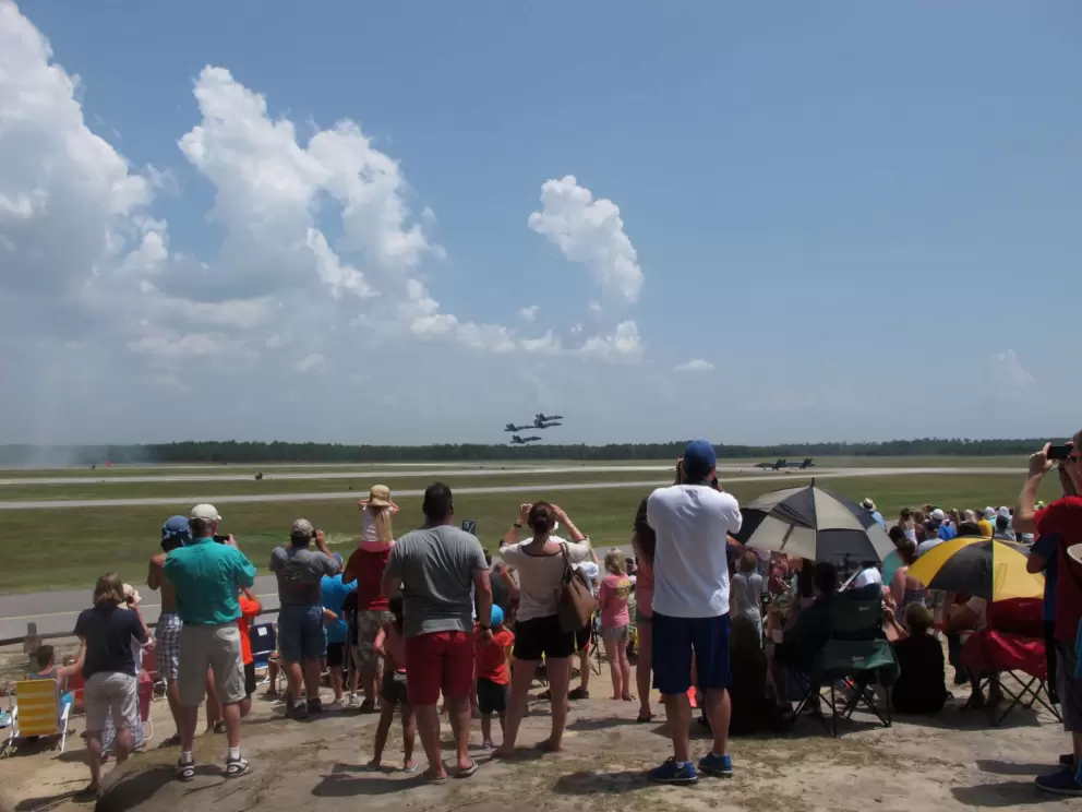 The crowd watching four planes fly low.