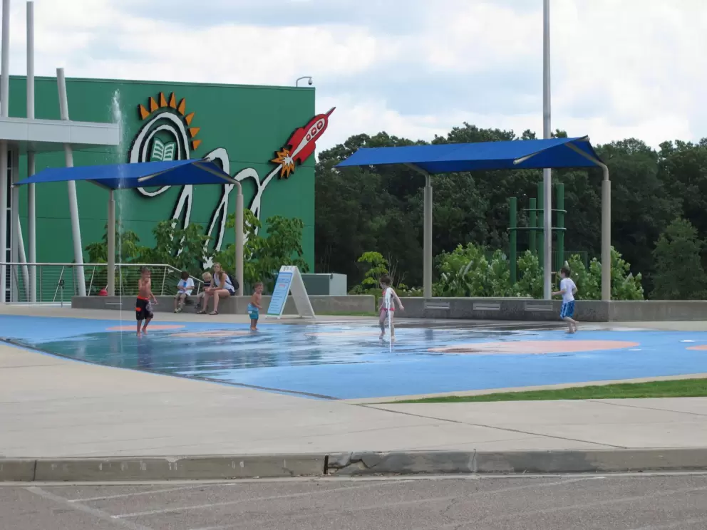 Splash pad outside the children's museum, with shade for parents.