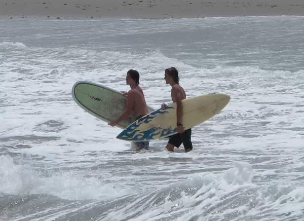 Boys entering the surf by the jetty.