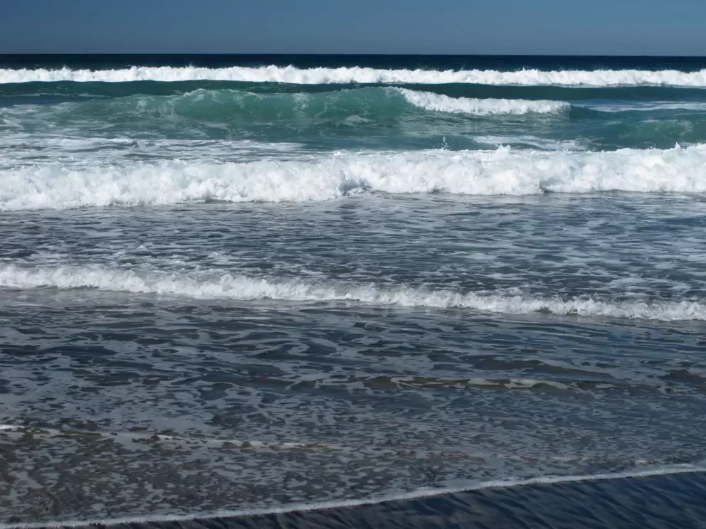 Dark sand and slate blue water.