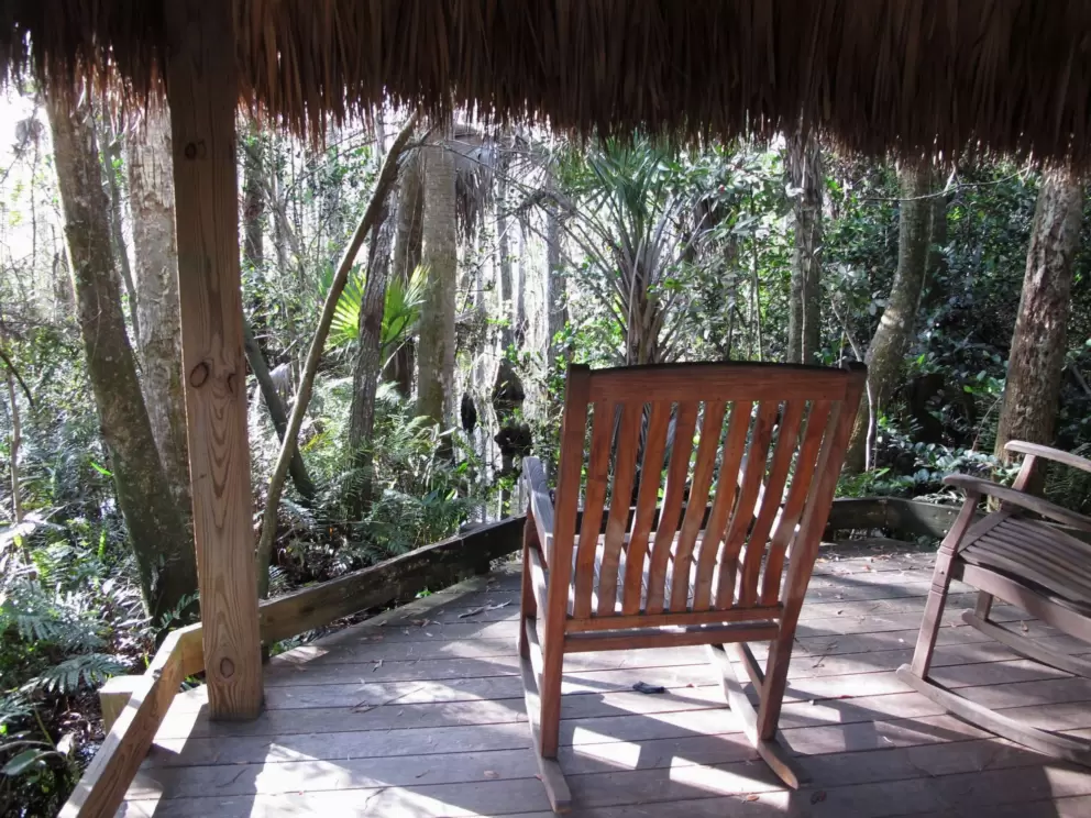 Rocking chair in the shade of a grass shack.