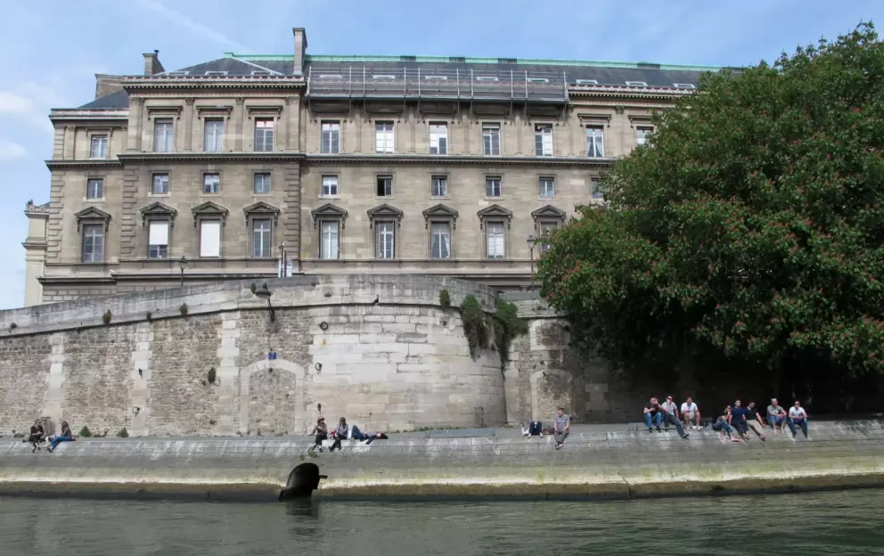 Friends sit together along the Seine.