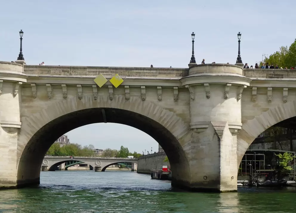 Cruising under Pont Neuf, a bridge of golden stone.