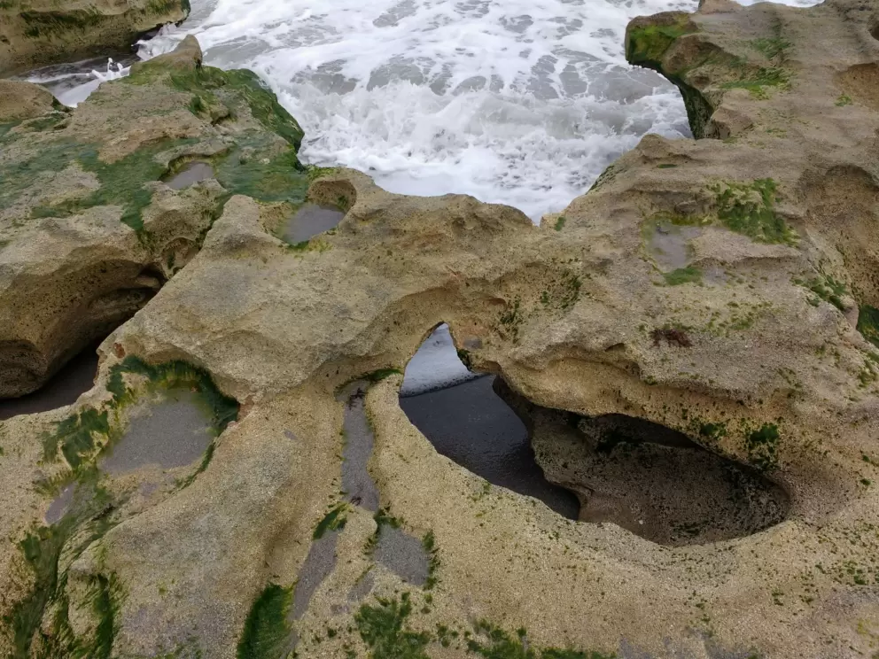 Water rushing under rock formations at Carlin Beach.