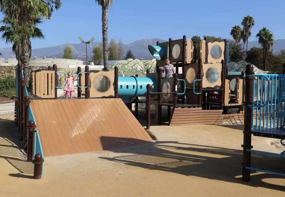 A little girl stands at the top of the slide.