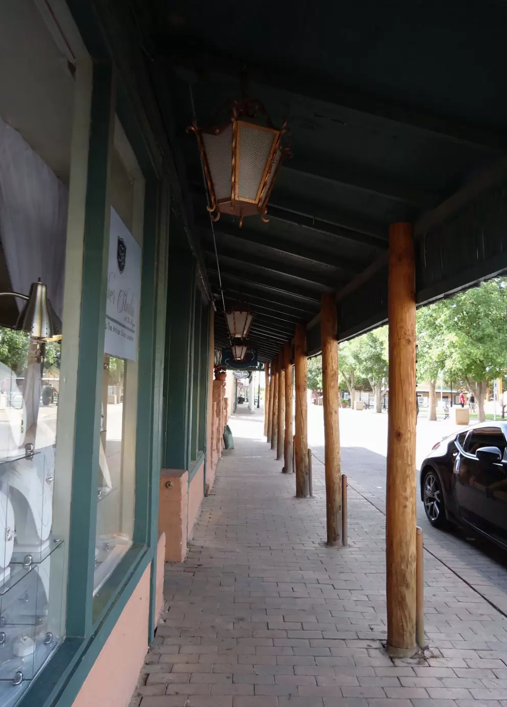 Shady walkway in front of historic storefronts.