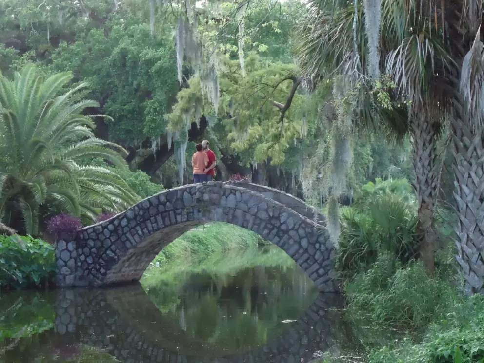A couple kisses on a stone bridge.