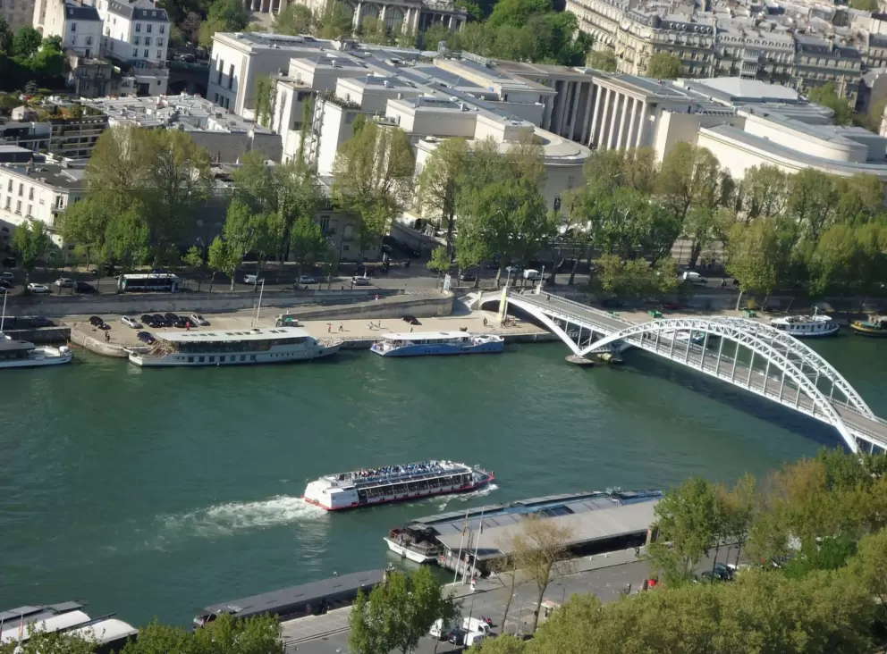 A boat making its way up the Seine river near the Eiffel Tower, as seen from the Eiffel Tower first level.