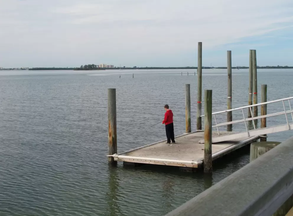 A boy goes fishing from a dock on the pier.