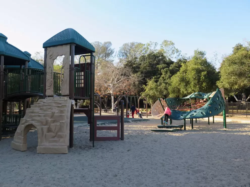 Play structure for big kids, sandy floor, climby, and swings.