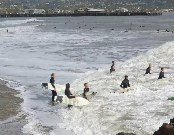 Young surfers attempting to get in the water at the end of the breakwater, on a high surf day.