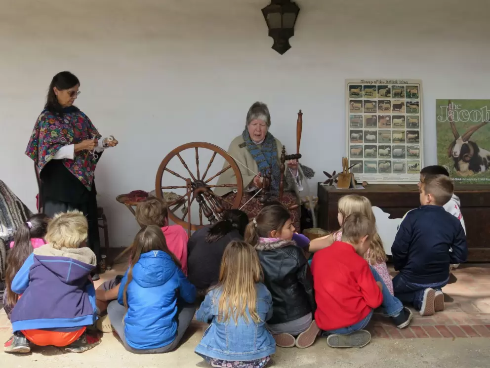 A school group watches a spinning demonstration at the presidio.
