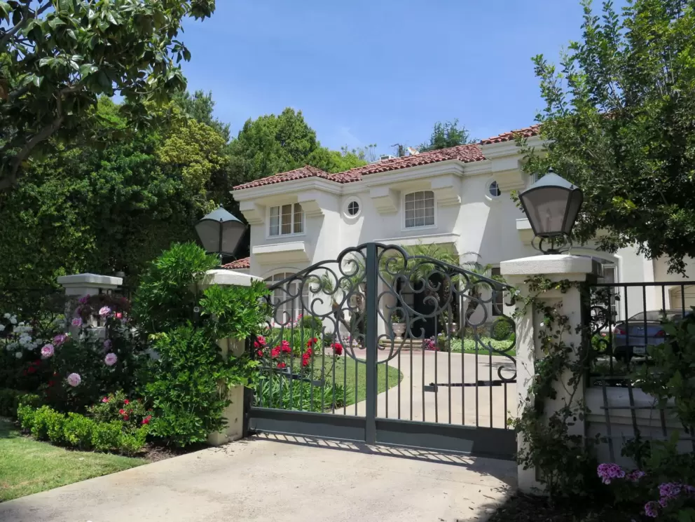 A mansion with a fancy fence and rose garden, on N. Beverly Dr.