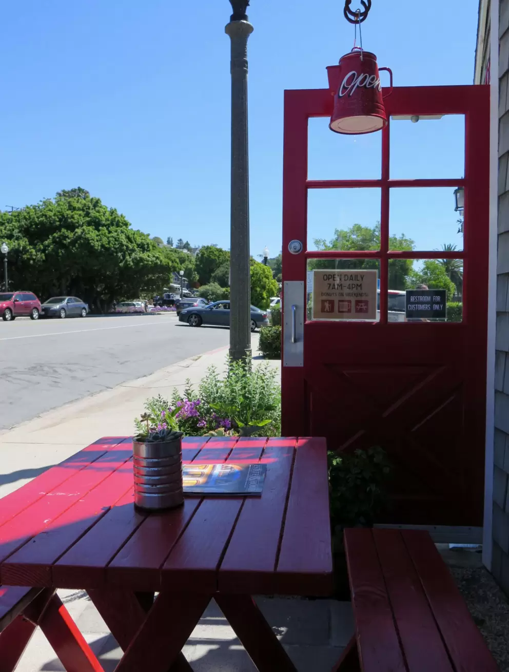 Cute red coffee kettle hanging over the door.