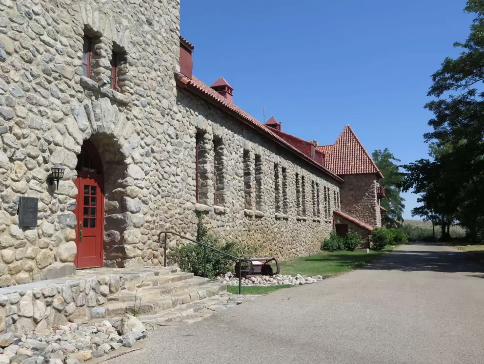 The long, stone building with a red door.