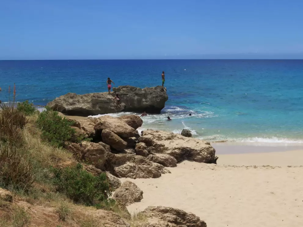 A young man stands on the rock ready to jump in.