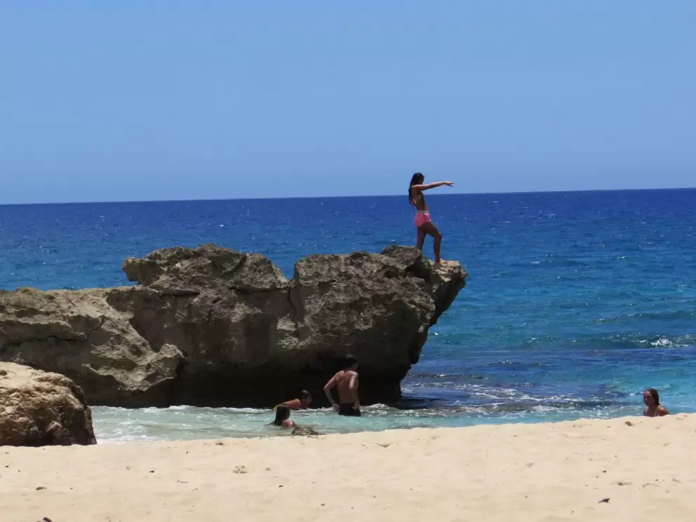 A young woman gets ready to jump off the rock.